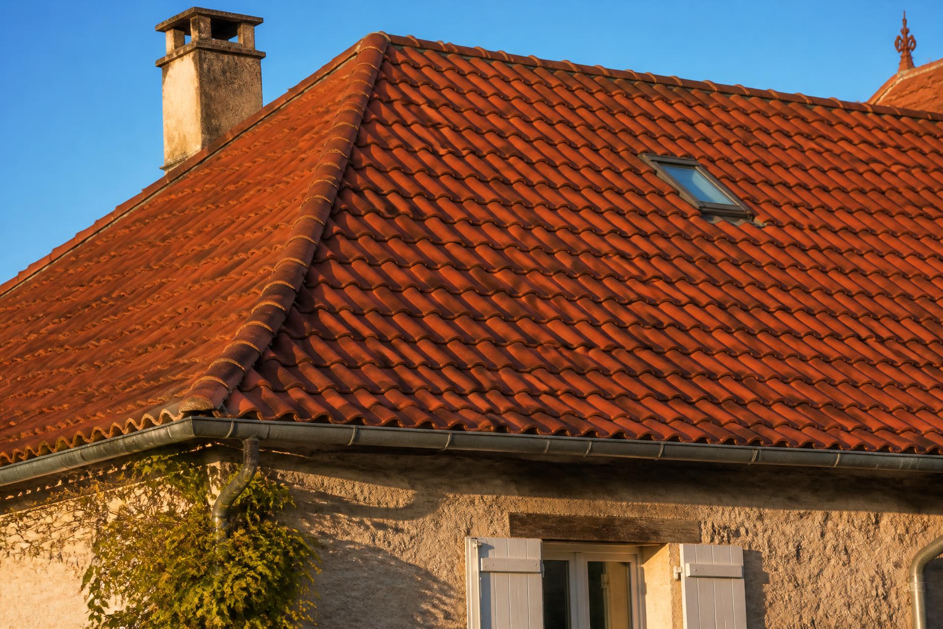 Toiture en tuiles terre cuite rénovée d'une maison du Sud-Ouest sous un ciel bleu